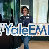 Margaret Alabi ’25 holding a sign that reads “#YaleEMBA”