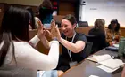 Two women giving each other high-fives in the classroom.