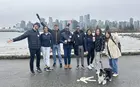 A group of students posing with the Vancouver skyline in the background