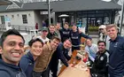 Members of the SOM United soccer team gathered around a picnic table sharing a meal