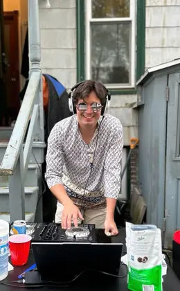 A person wearing headphones posing with a DJ turntable