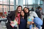 Three students holding books and smiling