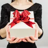 woman in black shirt holding white gift box with red ribbon