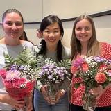 three students holding flower arrangements
