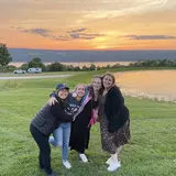 four students in front of a sunset