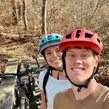 two people with bike helmets taking a selfie outdoors