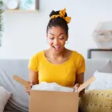woman in yellow shirt opening a package with surprise