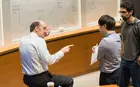 A professor talking with two students in from of a white board