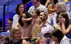 Toddler in crowd, held on lap and pointing to the stage