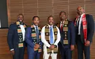 Five graduates in suits, wearing sashes and directly facing the camera