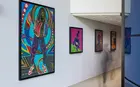 An exhibit of artwork with a blurred figure walking by