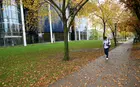 A student walking in front of the Yale SOM campus in autumn