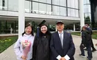 A graduating student and two family members posing in front of Evans Hall