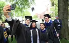 Four graduating students wearing caps and gowns taking a selfie