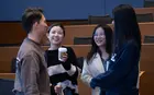 A group of students chatting and drinking coffee in a classroom