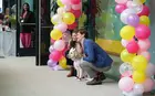 Two people pose with a dog under an arch of balloons