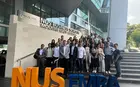 A group of students posing in front of a National University of Singapore building