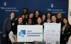 Several people posing with a sign reading “Yale Philanthropy Conference”