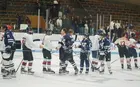 Hockey players from opposing teams shaking hands on an ice rink.