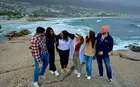 A group of people standing on a rocky cliff near a body of water