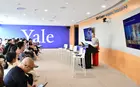 A person standing at a podium in a meeting room giving a presentation