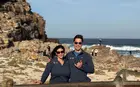 Two people standing on a rocky seaside outcropping, behind a sign that says “Cape of Good Hope“