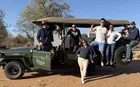Several people standing in and around an open vehicle on a safari