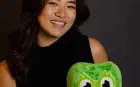 A person holding a green stuffed owl 