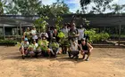 Several people holding tree saplings in a farm facility