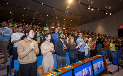 Students applauding and waving Ukrainian flags