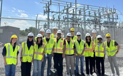 A group of people wearing reflective vests and hard helmets visiting a construction site