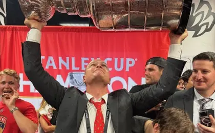 A person wearing a suit and lifting the Stanley Cup hockey trophy over his head