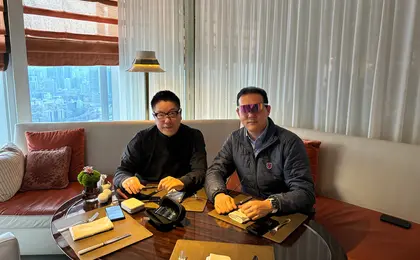 Two people sitting on a couch, one wearing augmented reality glasses