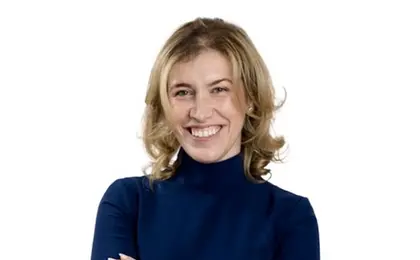 A headshot of a person with crossed arms smiling