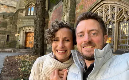 Two people taking a selfie outside a building with a Gothic facade