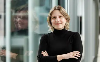 A heashot of a smiling person with a glass wall in the background