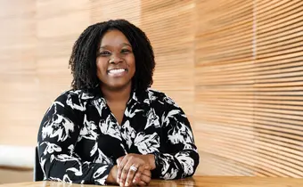 A smiling person photographed against a wood wall