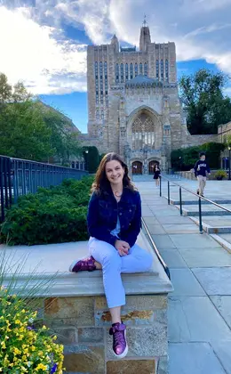 person sitting outside Sterling Memorial Library on the Yale campus