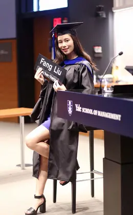 Fang Lui in classroom in graduation cap and robe