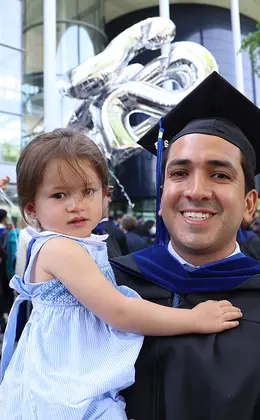 father in commencement attire holding child