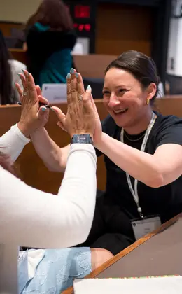 Two women giving each other high-fives in the classroom.