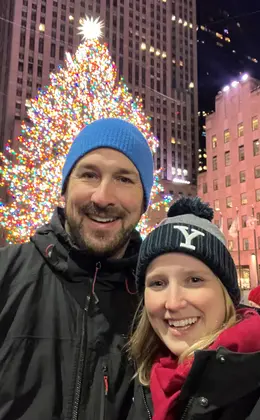 two people in front of a large, lit Christmas tree at Rockefeller Center