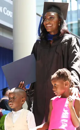 A graduating student walking across the stage with two children