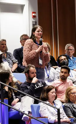 A student standing to ask a question during a panel discussion