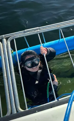 Two people in scuba gear preparing for a cage-diving expedition