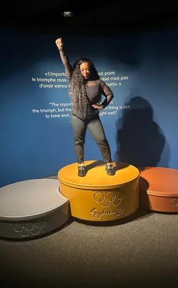 A person posing on top of a model Olympic podium