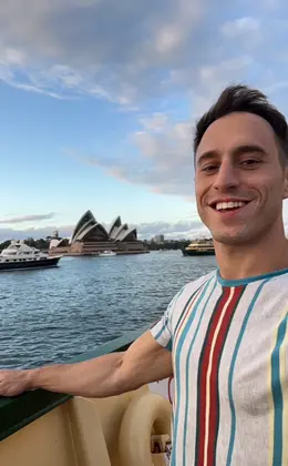 A person taking a selfie with the Sydney Opera House in the background