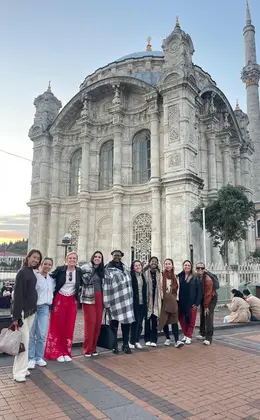 A group of people standing outside a large stone mosque
