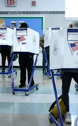 Three voting booths with people filling out ballots inside