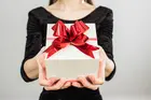 woman in black shirt holding white gift box with red ribbon